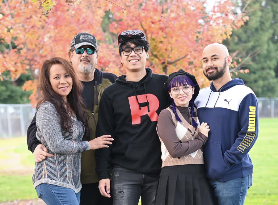 A family of five in front of turning autumn foliage