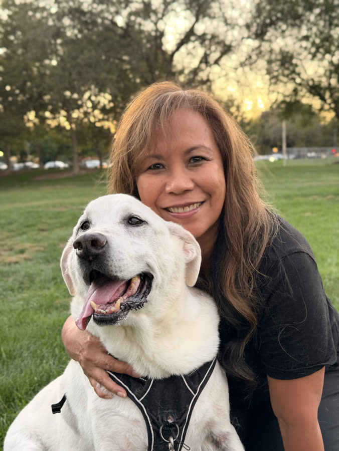 A woman hugging her yellow lab in golden evening light