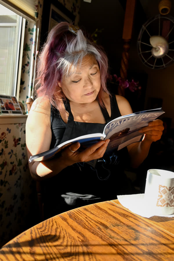 A woman reading at a sunlit kitchen table