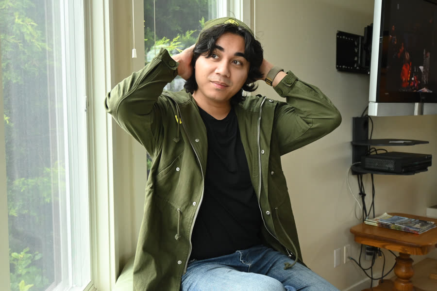 A young person in an olive parka lit by a bright window